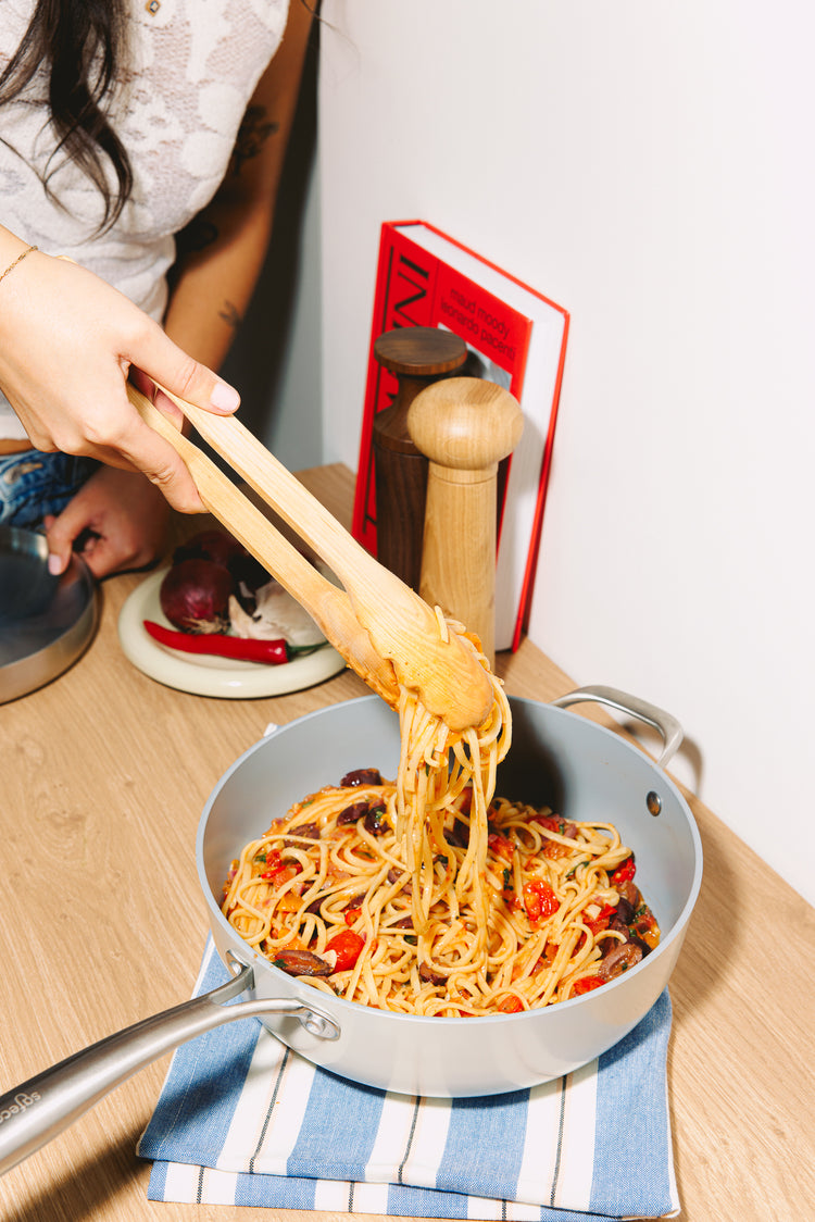 Pasta uit een keramische sautépan scheppen