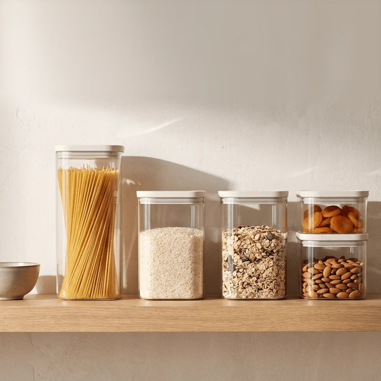 Glazen voorraadpotten met pasta, rijst, muesli en noten op een plank